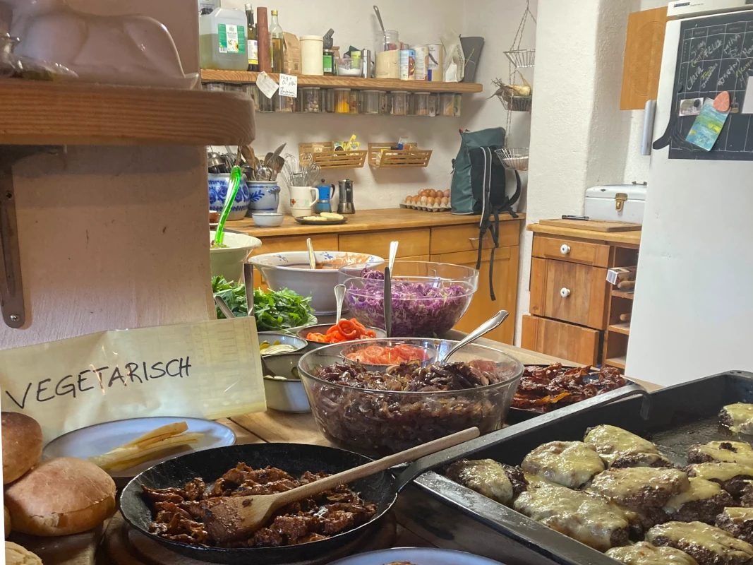 Gemeinsames Burger-Essen auf dem Hof Reichhaltiges Burger-Buffet in einer rustikalen Hofküche mit Käse-Patties, Salaten und einer vegetarischen Option in einer Gusseisenpfanne.